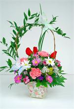 Butterfly container filled with bright color pink carnations, with mini carnations, wax flowers, lavender spray daisies, blue statice, million star gyp, bear grass, red roses, curly willow and italian ruscus handle with mixed greens and two butterflys.