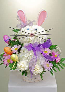 A perfect gift for the young and young at heart, the LaRosa's Easter flower Bunny. Designed with white Hydrangea and long lasting white carnations, we added pink and white satin ears, eyes, a pink nose and whiskers. We didn't stop there, we also added a b