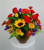 Designed in a amber glass vase this centerpiece has everyone favorite fall flowers. Bright yellow sunflowers with orange and yellow gerbera, red roses, a mixture of fall colored dasies and mums, red carnations, yellow solid ago with blue statice, hypericu