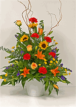 Designed with red carnations, orange asiatic lilies, with orange roses, yellow spray button pomps, mixed greens, baby eucalyptus and curly willow. Sending flowers for a friend or loved one at this difficult time shows that you care. When words fail us, fl