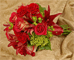 Shades of mixed colored red roses with green hydrangea, red lilies and green hypericum, with salal tips tied with matching ribbons.