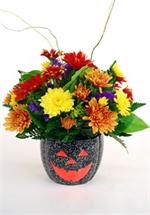 This colorful ceramic jack-o-lantern is filled with yellow, bronze, reds,and gold colored spray mums mixed with purple statice mixed greens and curly willow. Send 